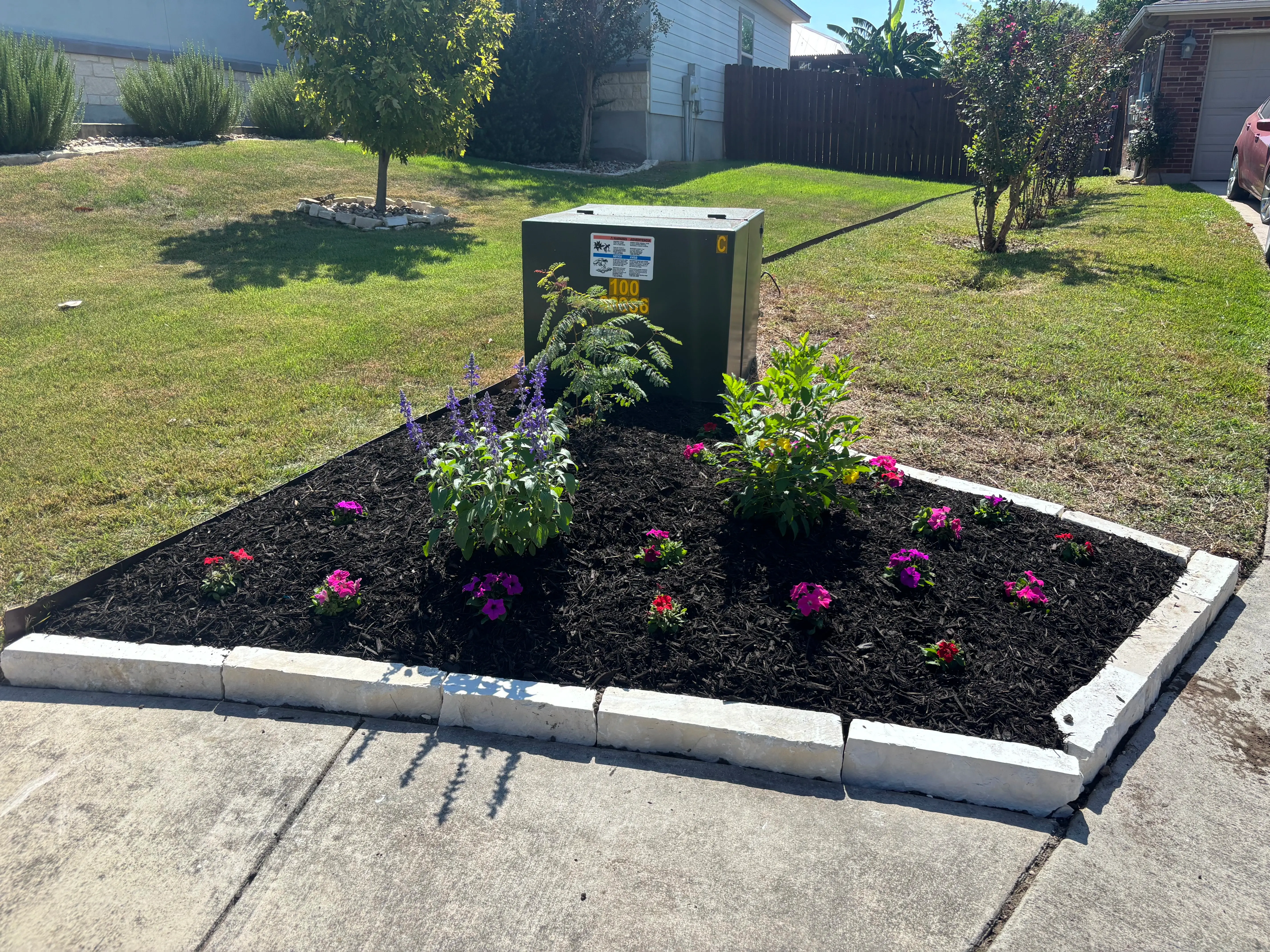 Newly done flower bed besides an electrical box.